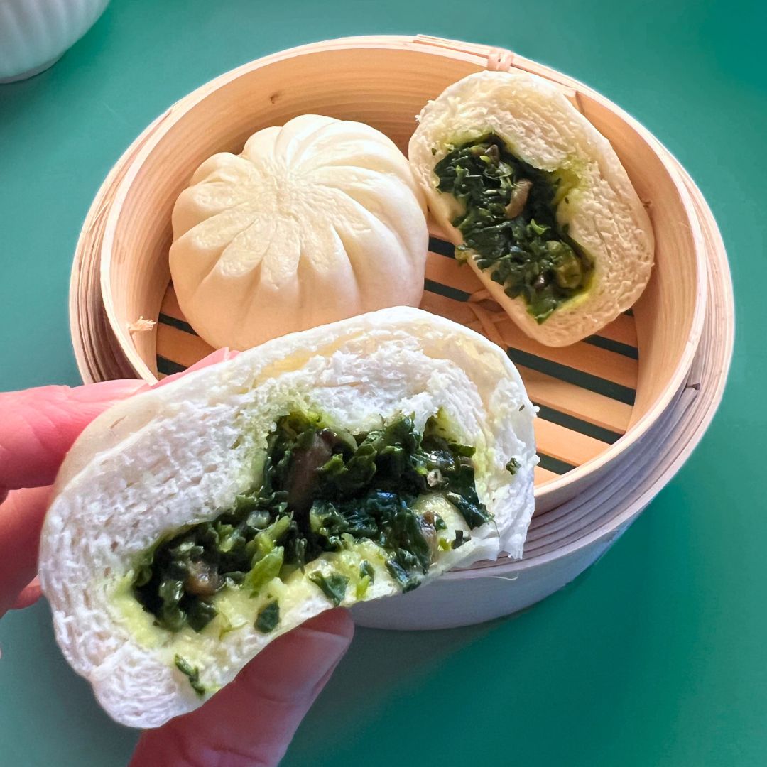 Steamed vegetable bun from the Ding Dong Dim Sum pescatarian box, opened to show the pak choi and mushroom filling during a home Lunar New Year meal.